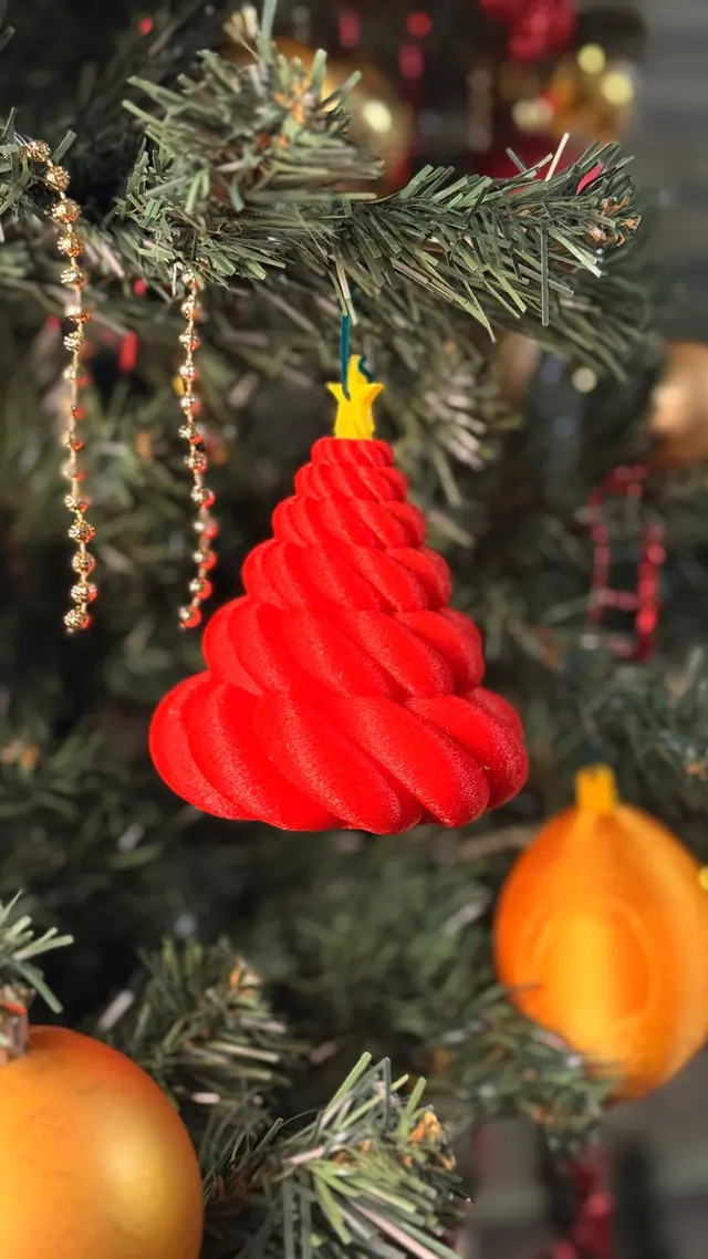 The little red tree hanging from a branch of the Christmas tree