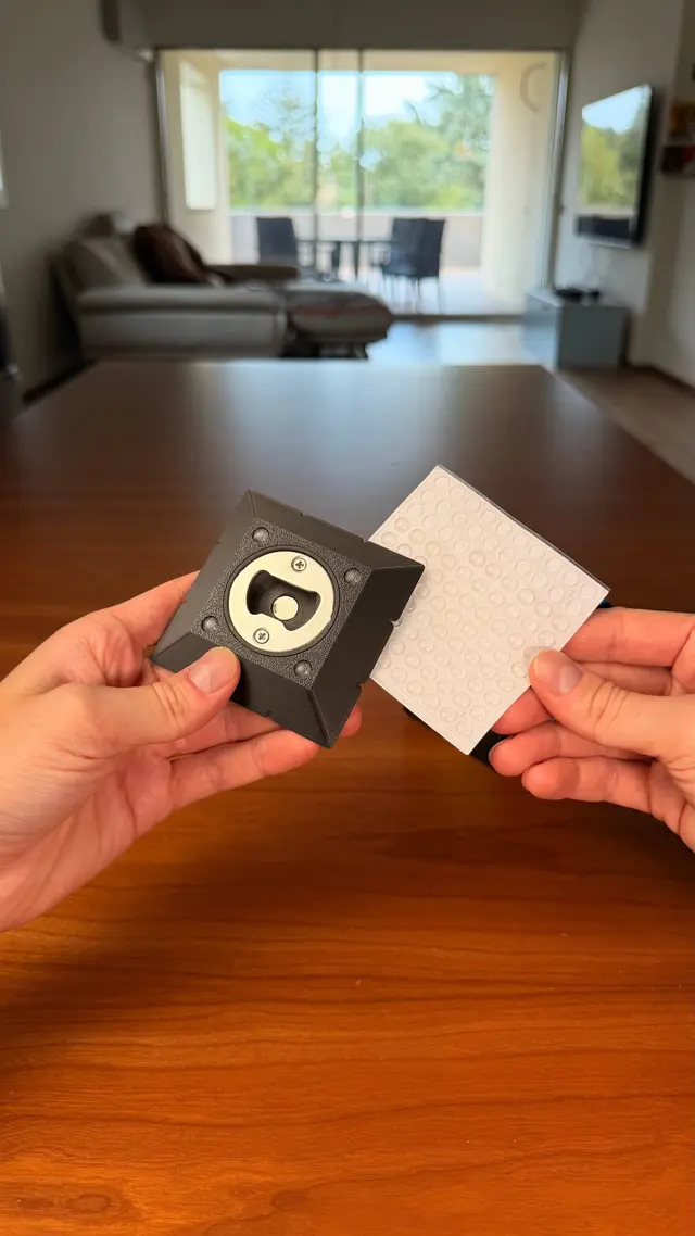 A white coaster and a black piece with the bottle opener