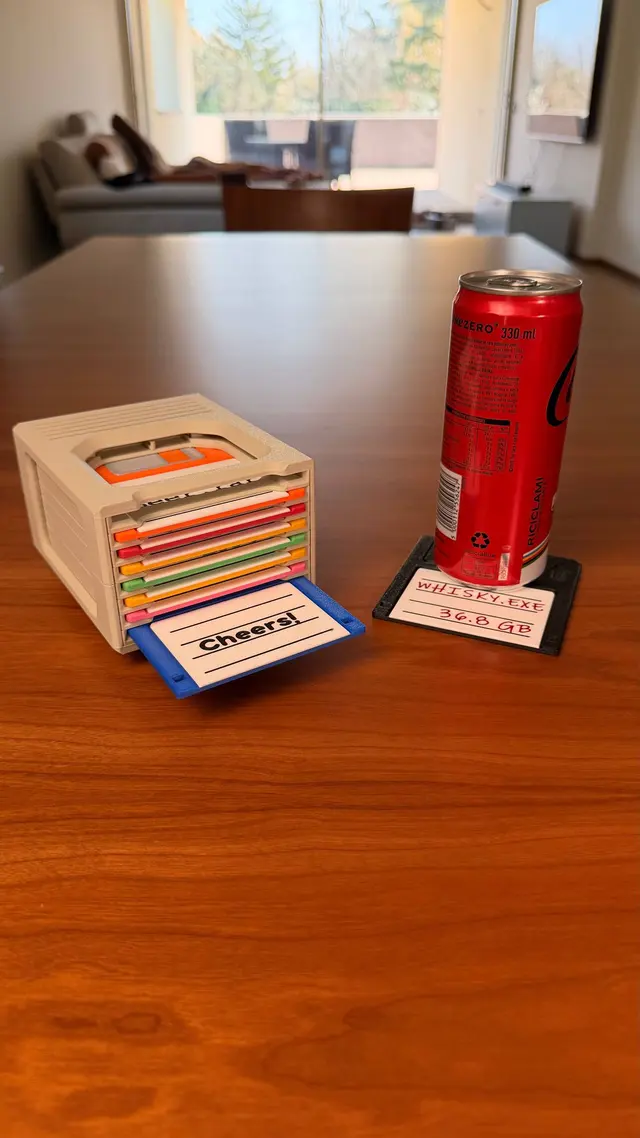 Floppy blu che esce dallo scomparto in basso; accanto una lattina appoggiata su un floppy nero