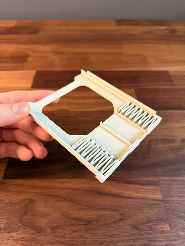 Un singolo scomparto tenuto in mano, con le due molle a zigzag e il perno stampati