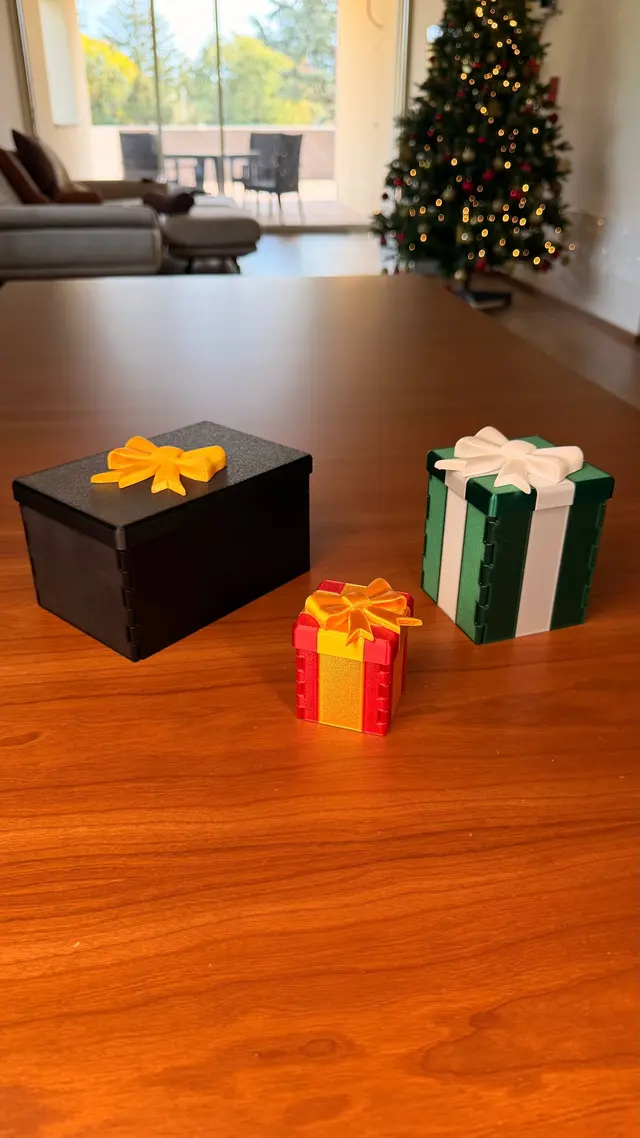 Three closed Gift Reveal boxes: black with an orange bow, red with a gold ribbon, green with a white ribbon