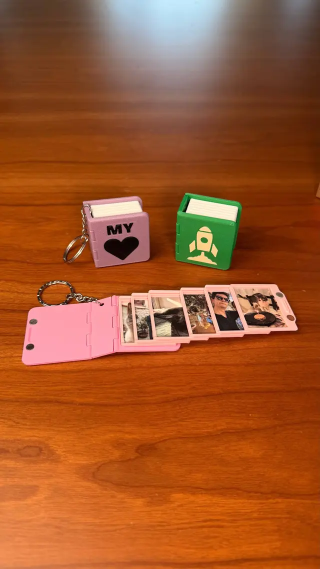 Un Key Book rosa aperto con le mini foto nelle pagine