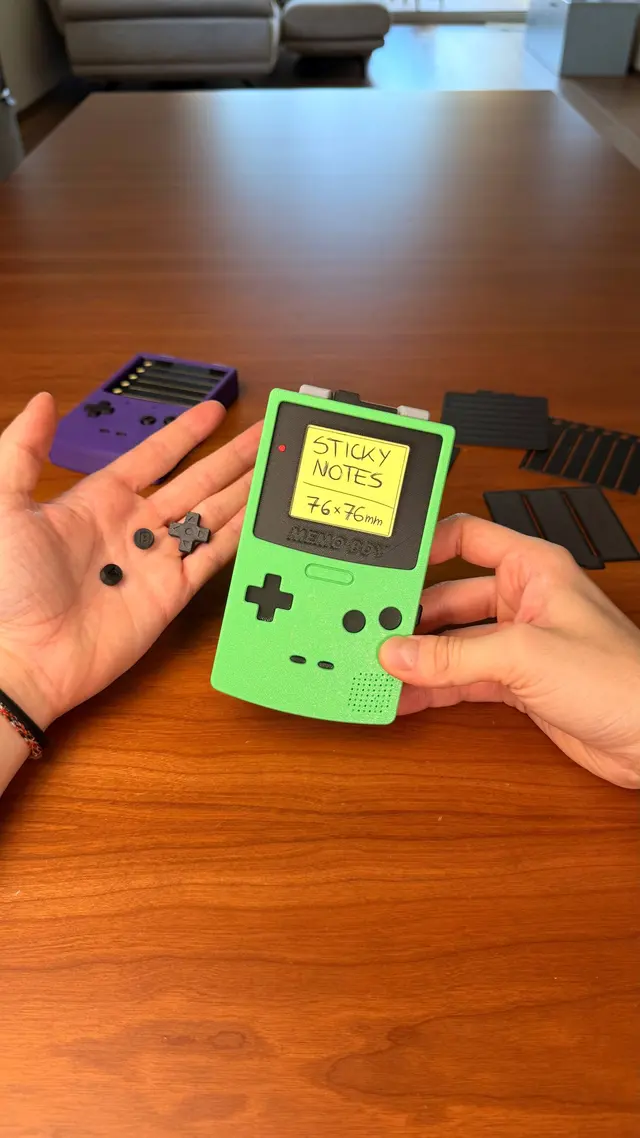 Two hands holding two Memo Boys, one green and one purple