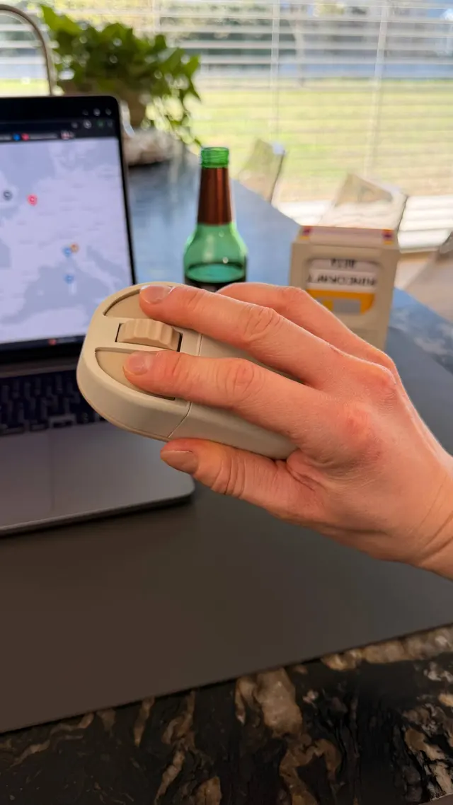 Mano che tiene il mouse beige con indice e medio appoggiati sui due tasti