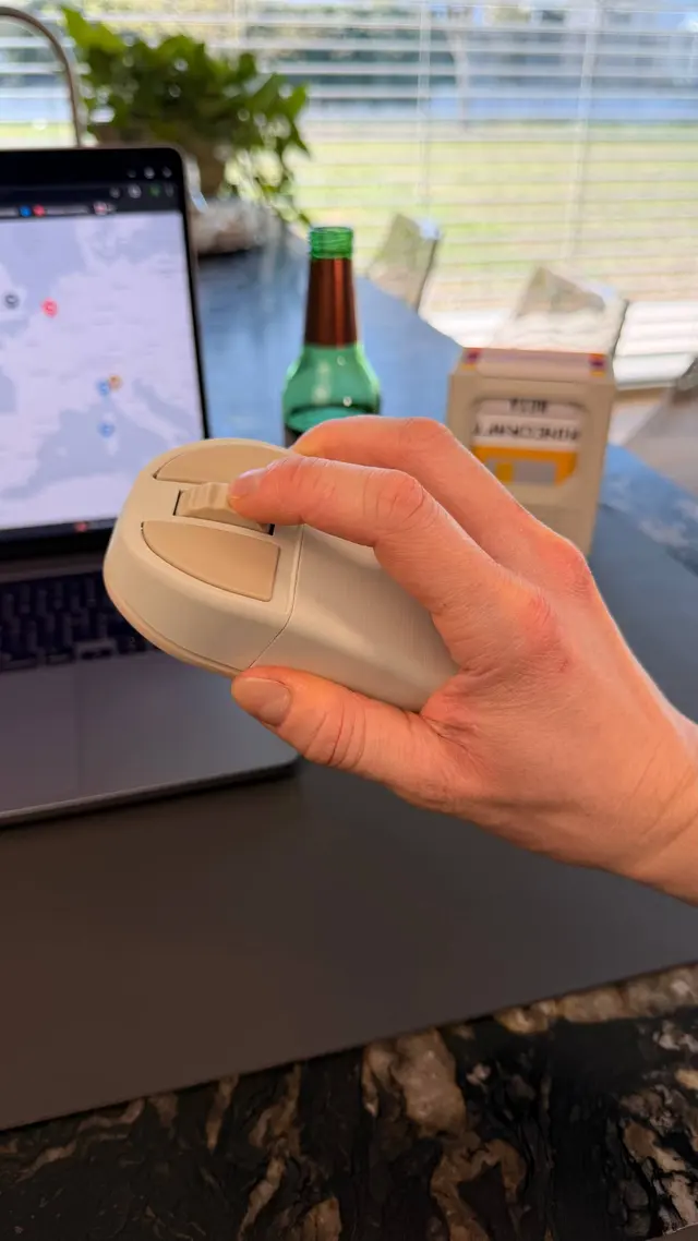 Mano che tiene il mouse beige mentre un dito gira la rotella centrale