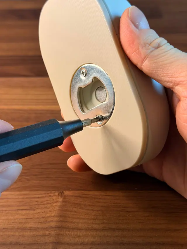 Inserto apribottiglie in metallo avvitato sul fondo del mouse, con il magnete visibile al centro