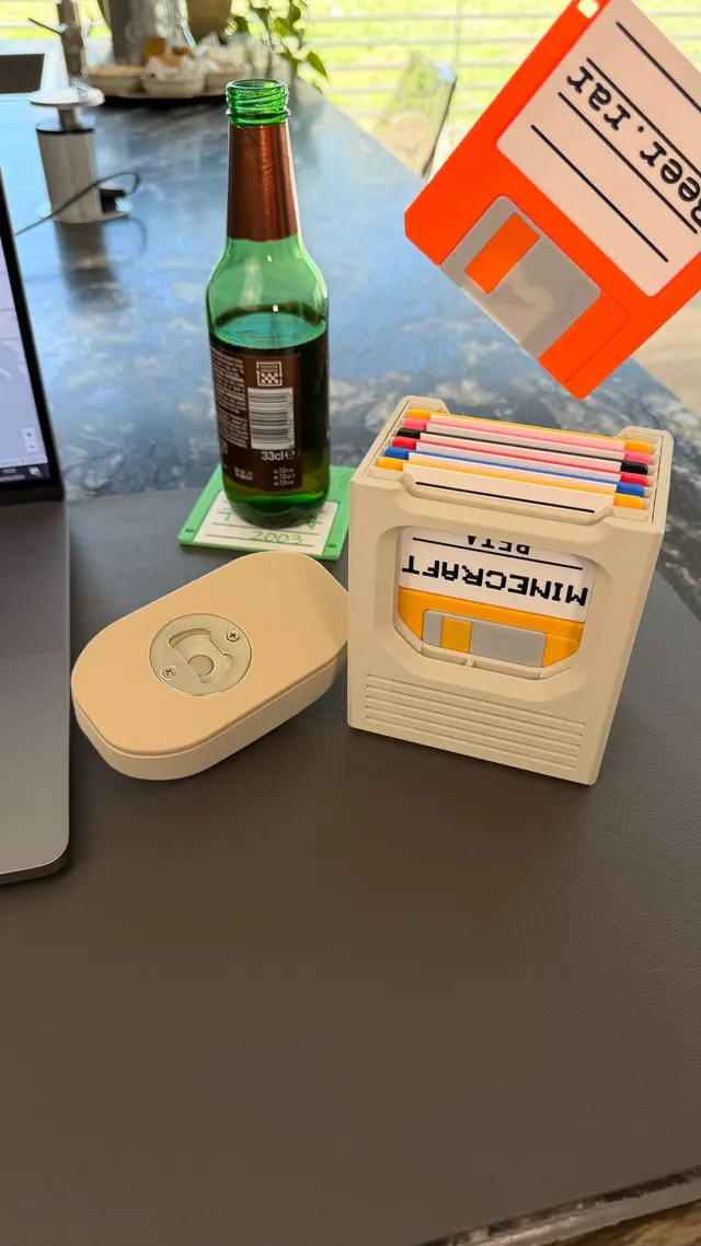 Mouse capovolto sulla scrivania con l'inserto apribottiglie in vista, accanto a bottiglia e box di floppy