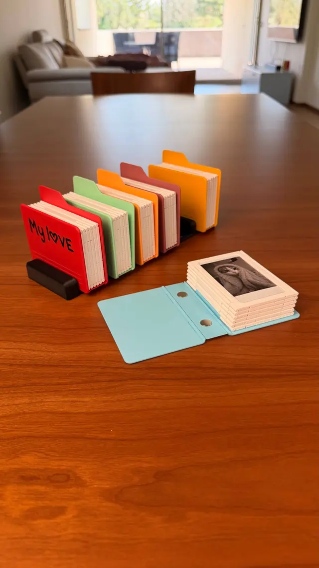 Light blue album opened flat with the frames stacked and the two magnets on the spine, more albums on the stand