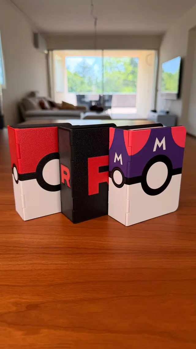 Three closed binders standing up: red and white ball, black with the letter R, purple ball with the letter M