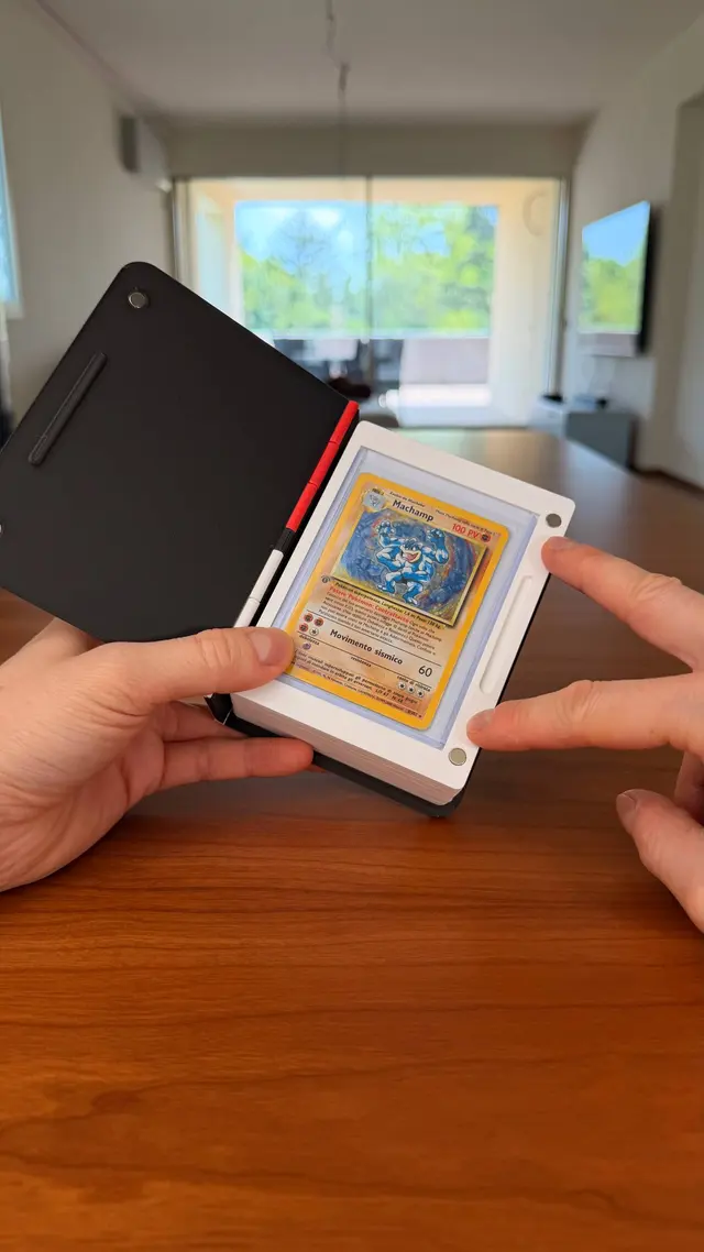 A binder open in a hand: the first page with a card in a toploader and closing magnets in the corners