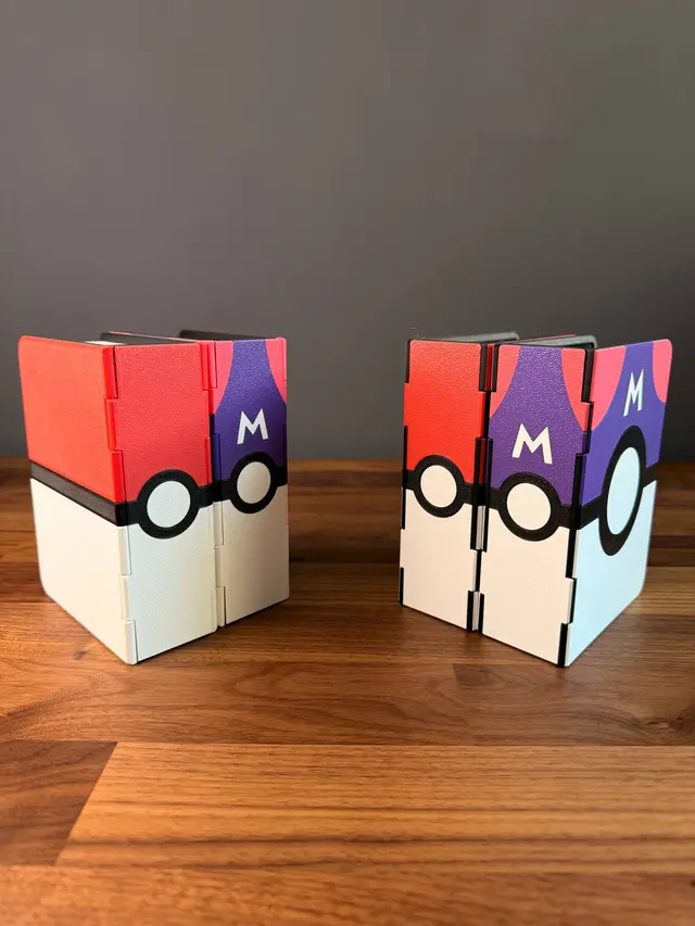 Four closed binders seen from the spine on a wooden surface, with a red and white ball and a purple ball