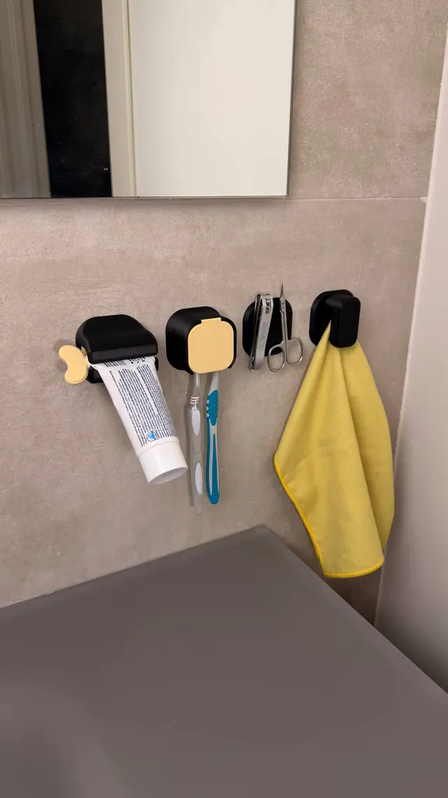 Black Tidy Wall organisers fixed to the bathroom wall, with toothpaste, toothbrushes and a towel