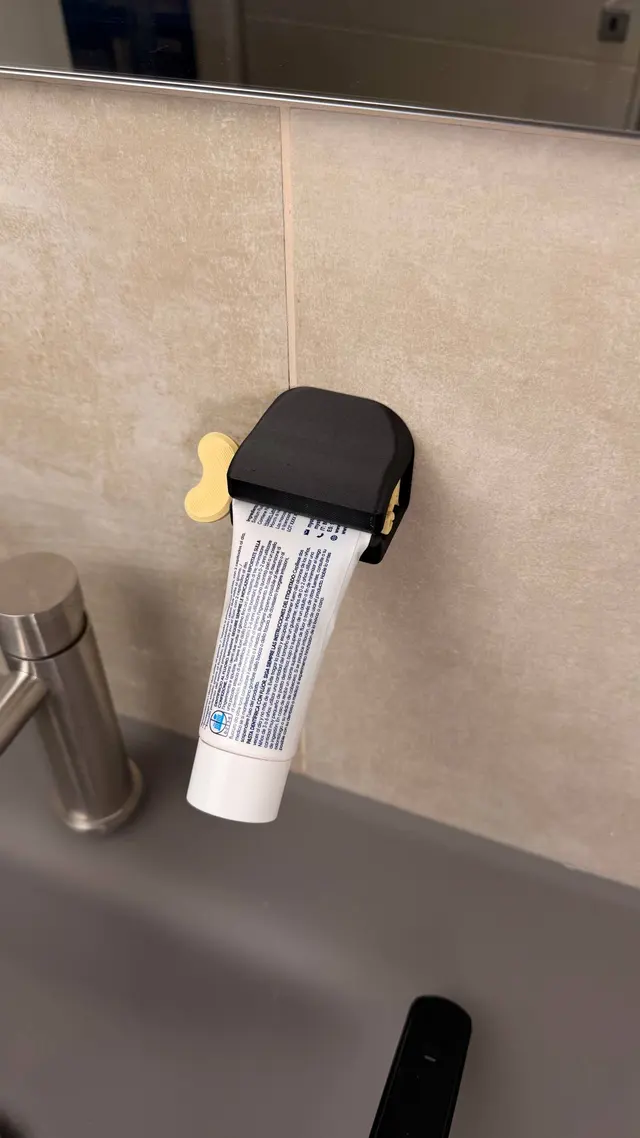 The key-style toothpaste squeezer with the tube slotted in