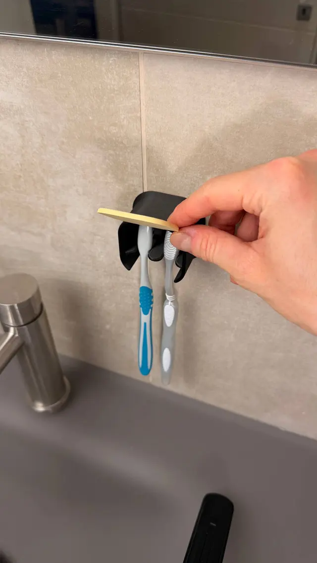 A hand opens the lid of the toothbrush holder